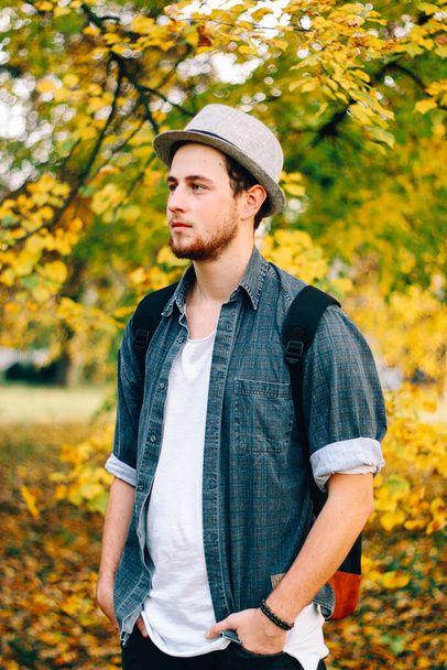 A vertical selective focus shot of an attractive guy in an autumn park - Valokuva, kuva