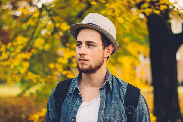A selective focus shot of an attractive guy in an autumn park - Fotoğraf, Görsel