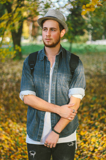 A vertical selective focus shot of an attractive guy in an autumn park - Foto, Imagen