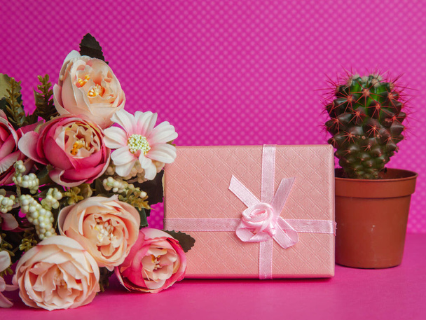 ピンクの背景に花やサボテンの入ったギフトボックス - 写真・画像