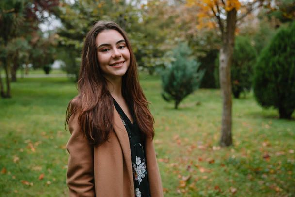 Portrait of young attractive woman in park. Woman in coat - Foto, imagen
