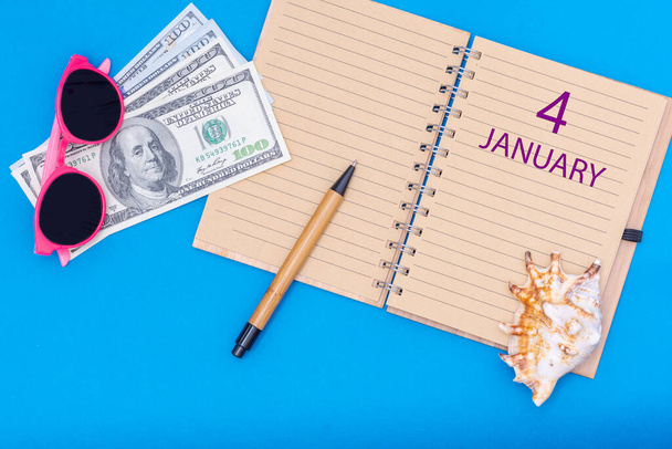4 January. 4th day of January. Travel plan flat design with notepad written date, pen, glasses, money dollars and seashell on blue background. Winter month, day of the year, calendar concept - Фото, изображение