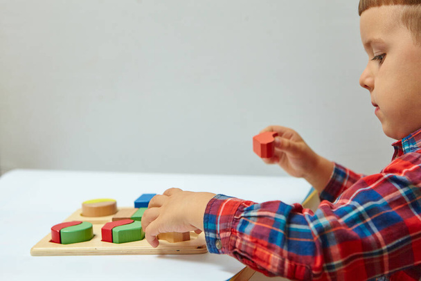 El chico está jugando en su habitación. Aprender formas y colores. Un niño juega con un clasificador. Juguetes de lógica educativa para niños. Juegos de Montessori para el Desarrollo Infantil. - Foto, Imagen