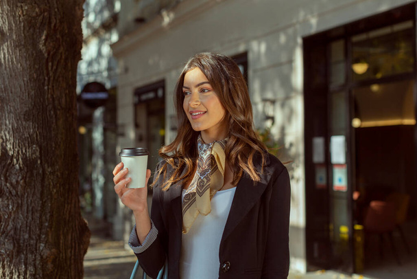  Beautiful woman with cup of coffee walking on street - Foto, imagen