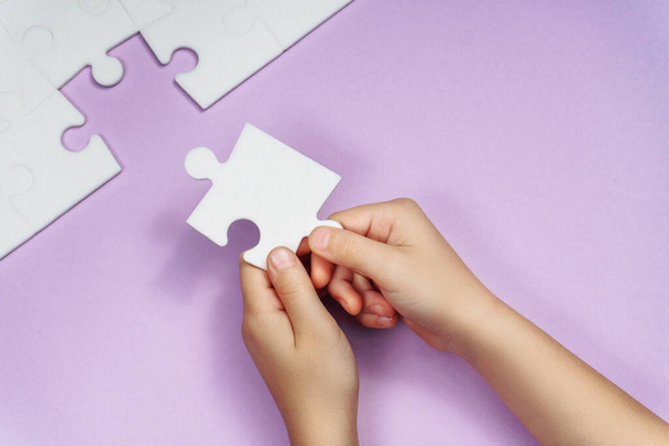 Kinderhände bilden das letzte fehlende Puzzleteil auf dem Veilchen. Strategie-Geschäftskonzept - Foto, Bild