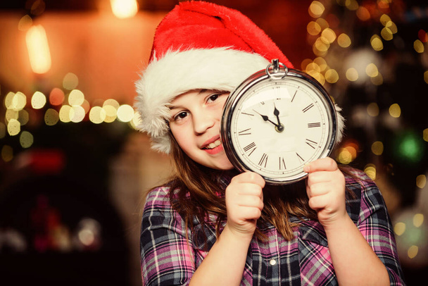 Few minutes till new year. Magic moment is coming. Girl santa claus hat and clock. Meet Christmas holiday. Festive atmosphere christmas day. New year countdown. Counting time. Christmas almost here - Фото, изображение