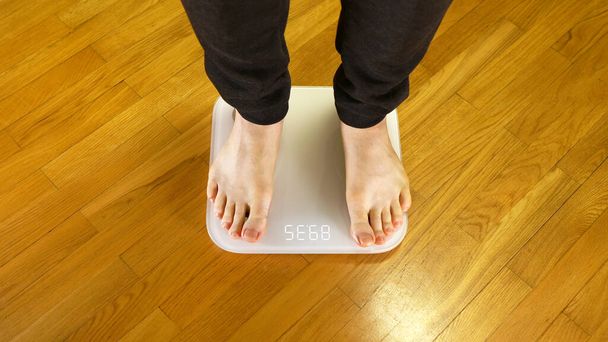 Legs on the scales. Man checking his weight. - Zdjęcie, obraz