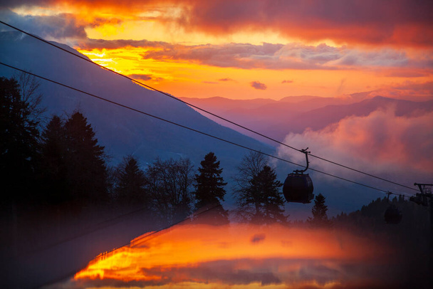 Krasnaya Polyana, Sochi, the mountains of the North Caucasus, snow-capped peaks against the background of autumn trees, red sunset over Krasnaya Polyana by cable car - Photo, Image