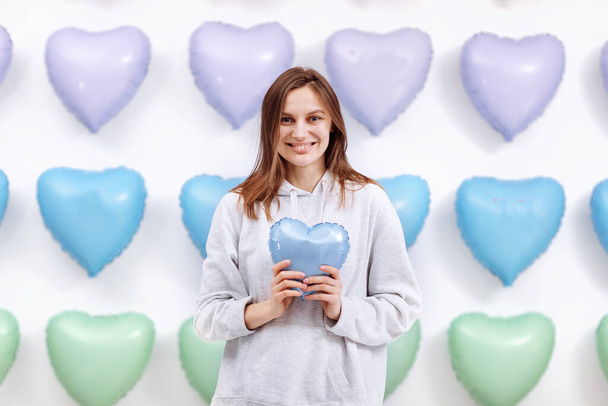 Žena drží modrý balón v podobě srdce na mnoha srdcích pozadí. Valentýn. selektivní zaměření. - Fotografie, Obrázek