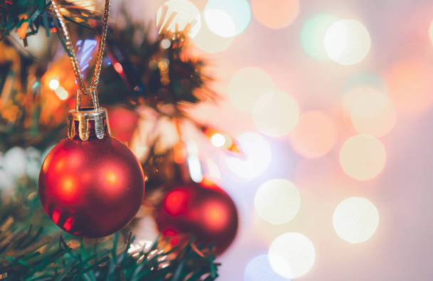 Karácsonyi dekoráció. Piros golyó lóg fenyő ágak karácsonyfa koszorú és díszek felett elvont bokeh háttér másolás tér - Fotó, kép