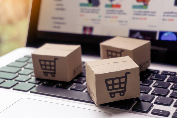 Online vásárlás - Papírdobozok vagy csomagok bevásárlókosár logóval egy laptop billentyűzeten. Bevásárlási szolgáltatás az online weben, és kínál házhozszállítás. - Fotó, kép