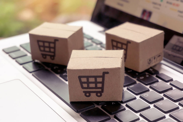 Online nakupování - Papírové krabice nebo balíček s logem nákupního košíku na klávesnici notebooku. Nákupní servis na webu a nabízí doručení domů. - Fotografie, Obrázek