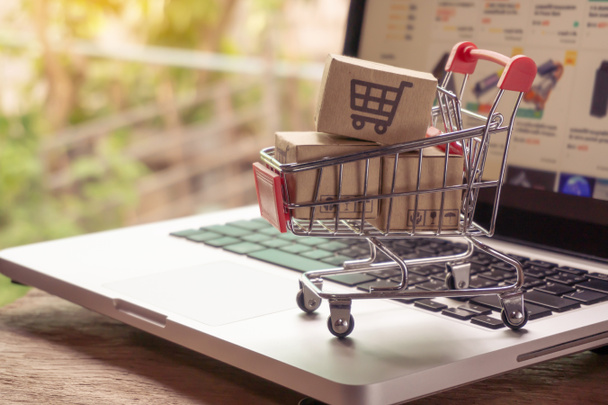 Shopping online concept - Parcel or Paper cartons with a shopping cart logo in a trolley on a laptop keyboard. Shopping service on The online web. offers home delivery - Foto, imagen