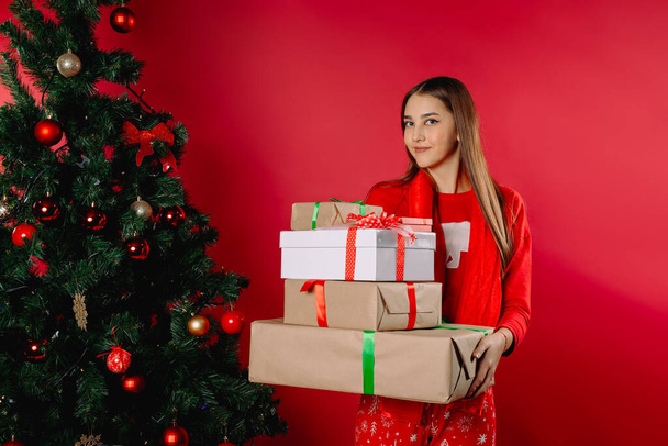 Girl in pajamas holding many gifts at home by the tree. Holiday concept. High quality photo - Valokuva, kuva