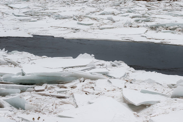 Παγωμένο ποτάμι. Μεγάλες πλάκες σπασμένου πάγου φράζουν το ποτάμι. Ο πάγος είναι κυρίως εύθραυστος..  - Φωτογραφία, εικόνα