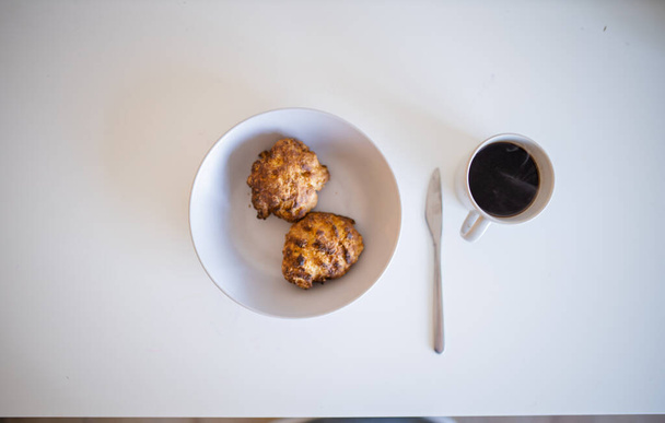 Dvě sušenky vedle šálku kávy na bílém stole - Fotografie, Obrázek