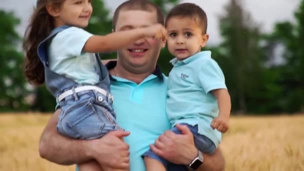 Pai está carregando sua filhinha e filho em seus braços no campo - Filmagem, Vídeo