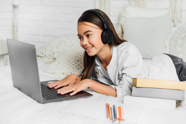 Smiling teen girl studying online at the computer. - Fotó, kép