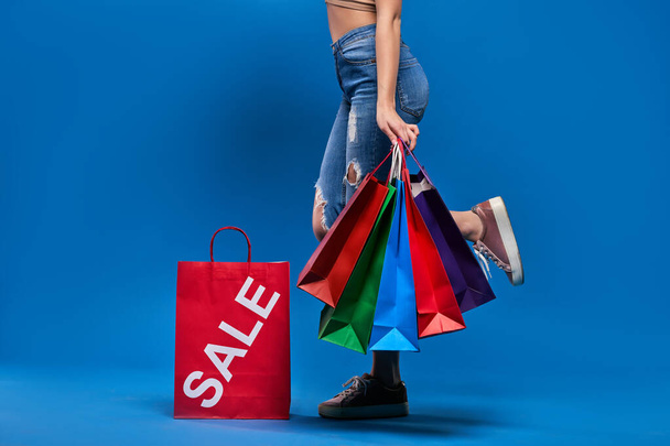 Girl holding bags for sale on a blue background. - Photo, Image