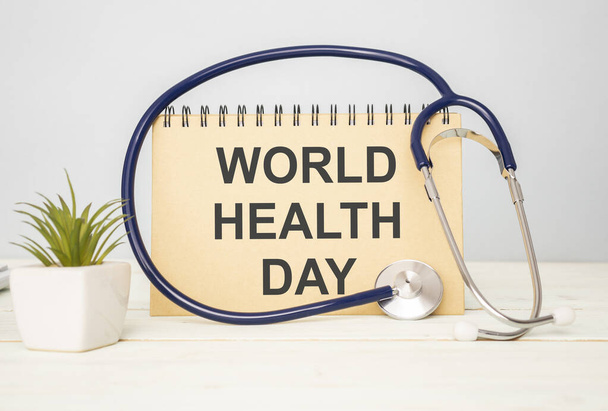 Stethoscope, white paper, with wooden board and inscription World Health Day on wooden background. - Photo, image