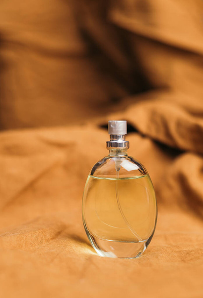 A bottle of women's fragrant perfume on a brown textured fabric background. - Photo, Image