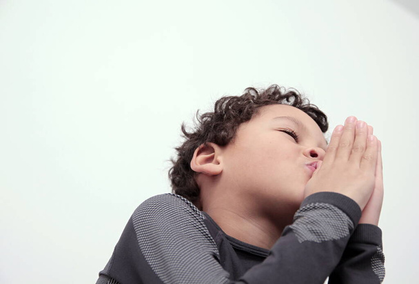 chłopiec modląc się do Boga z dłońmi razem na białym tle Zdjęcie - Zdjęcie, obraz