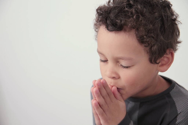niño rezando a Dios con las manos juntas sobre fondo blanco foto de stock - Foto, imagen