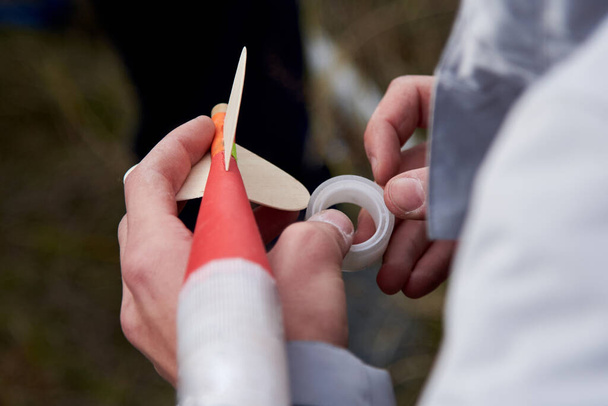 The guy holds in his hands a model of a miniature rocket and prepares it for flight. - Photo, Image