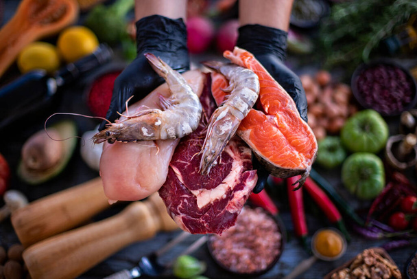 Ein Koch zeigt dem Kunden im Restaurant die Fleischsorten. Restaurantkonzept mit Rohkost.  - Foto, Bild