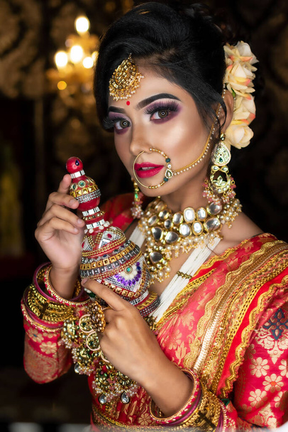 Retrato de novia india muy hermosa sosteniendo sindur tradicional de madera o caja sindoor en la mano, caja sindoor símbolo de la boda. - Foto, Imagen