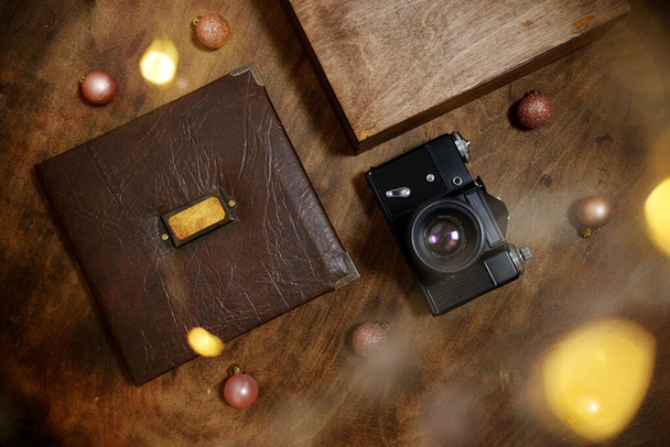 Cadeaufotoboek in een leren omslag in een houten multiplex doos met een vintage zwarte camera. Vintage fotoalbum. Semeinfe fotografeert het leven van één persoon. concept van Kerstmis aanwezig voor het gezin. - Foto, afbeelding