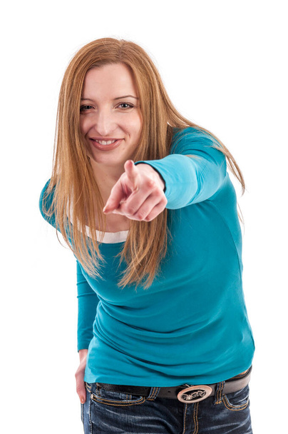 Портрет молодої блондинки у синьому светрі на білому тлі, що вказує лівим індексним пальцем до камери
. - Фото, зображення