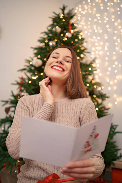 Schöne junge Frau liest eine Weihnachtsgrußkarte - Foto, Bild