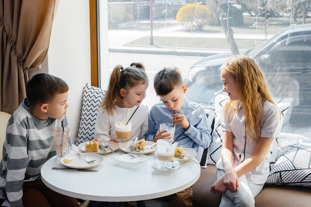A large friendly company of children celebrate the holiday in a cafe with a delicious dessert. The day of the birth - Photo, Image