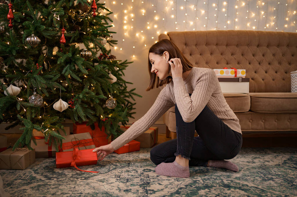 Woman putting gift boxes under Christmas tree - Foto, immagini
