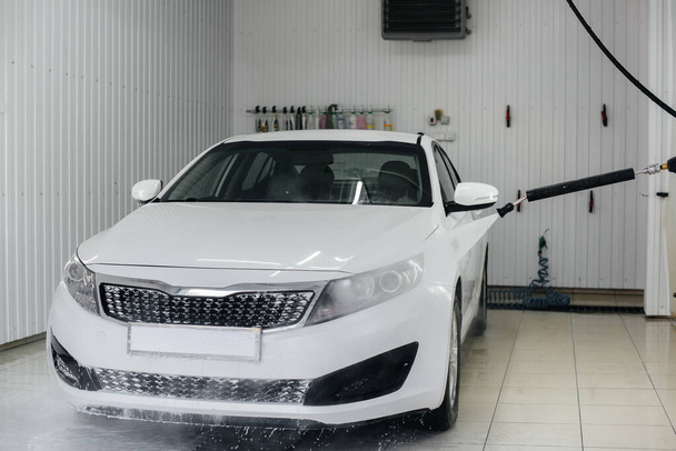 Modern washing with foam and high-pressure water of a white car. Car wash - Fotoğraf, Görsel