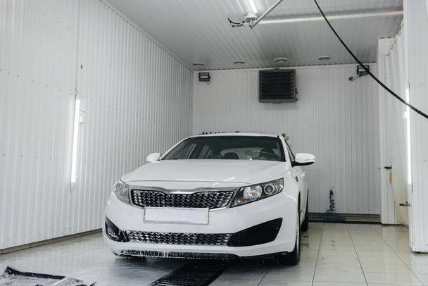 Modern washing with foam and high-pressure water of a white car. Car wash - Foto, Imagen