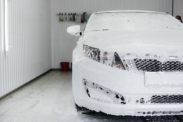 Modern washing with foam and high-pressure water of a white car. Car wash - Φωτογραφία, εικόνα