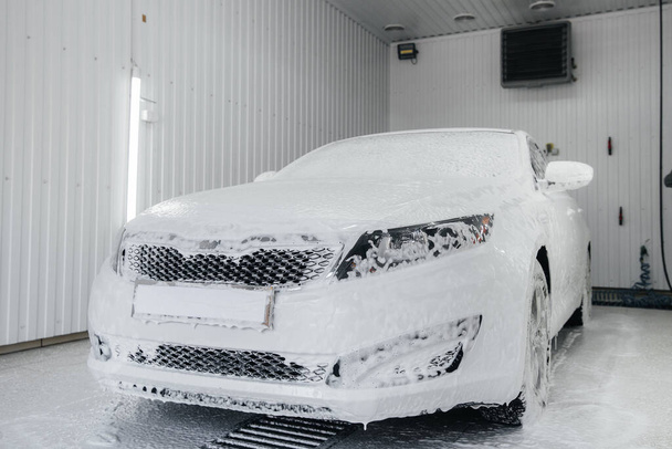 Modern washing with foam and high-pressure water of a white car. Car wash - Photo, Image