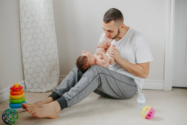 Fathers Day holiday. Caucasian father playing kissing  newborn baby. Parent holding rocking cute funny child daughter son. Authentic lifestyle candid tender moment. Single dad family life. - Photo, image