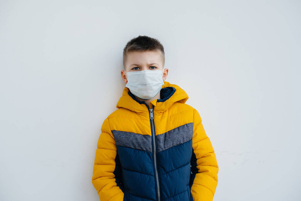 A boy stands on a gray background in a mask during a quarantine with free space. Quarantine in the mask - Foto, immagini