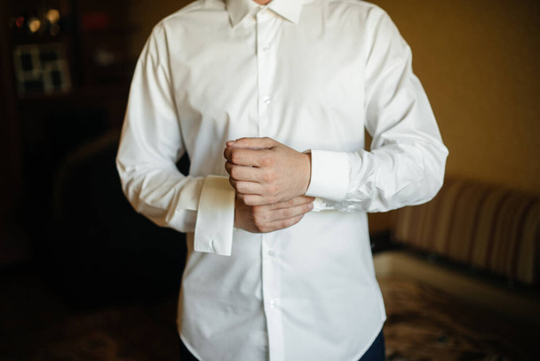 Stylish young man buttoning the cuff links on the sleeves. Style - Photo, image
