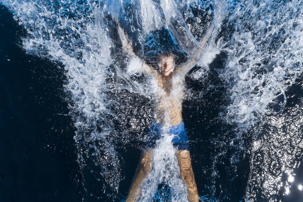 Man jumping and splashing in black swimming pool - Valokuva, kuva