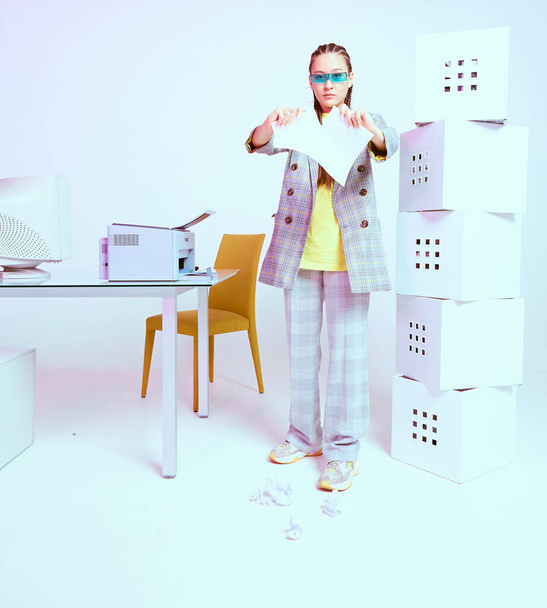 Stylish asian female office worker rips a sheet of paper near printer and boxes. Colored Neon light - Zdjęcie, obraz