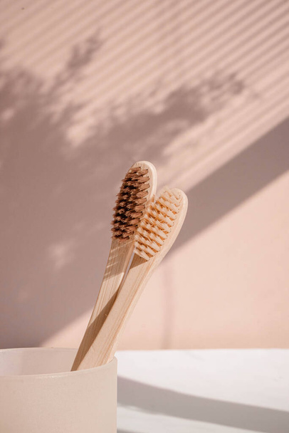 Cepillo de dientes de bambú de cero residuos sobre fondo pastel con tonos florales. Foto de alta calidad - Foto, imagen