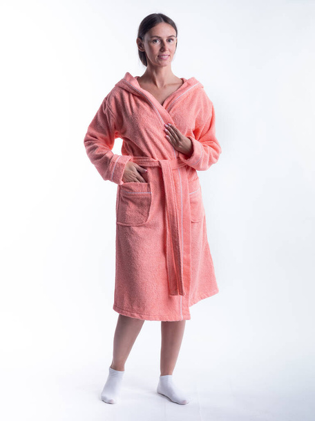 woman in a Bathrobe on an isolated white background with a smile on her face. Shot in the Studio in full growth. - Foto, Imagen