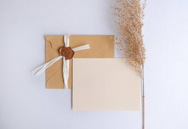 Craft envelope with business card mock up decorated wtih pampas grass on white background . High quality photo - Φωτογραφία, εικόνα