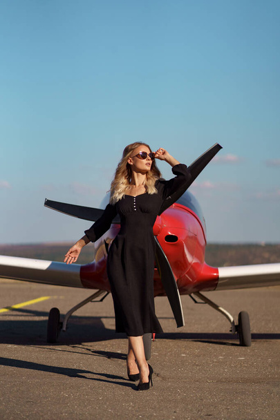 Glamoureuze vrouw poseren op vliegtuig achtergrond - Foto, afbeelding
