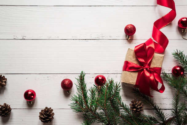 Noel oyuncakları, çam kozalakları, kırmızı kurdeleli bir hediye, beyaz ahşap bir masada ladin dalları. - Fotoğraf, Görsel