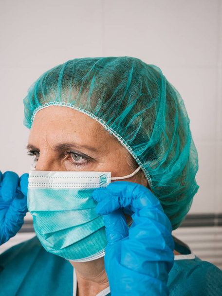 Muotokuva terveydenhuollon ammattilainen nainen suojaa covid 19 laittaa hänen naamio - Valokuva, kuva